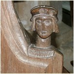 Carved head of a man on back pew.