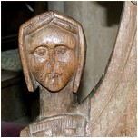 carved head of a woman on back pew.